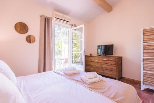 a bedroom with a bed and a tv and a window at Les Maisons Du Sud in Saint-Tropez