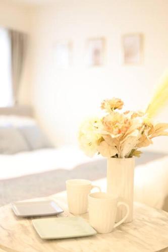 a vase with flowers and two cups on a table at Miu Hotel Shinagawa - Tokyo Travel Hub near Landmarks, Bullet Train & Airport in Tokyo