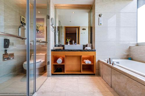 a bathroom with a tub and a toilet and a sink at Felton Grand Hotel Chengdu in Chengdu