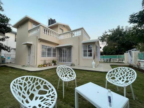 two chairs and a table in front of a house at Bungalow No 11 Parvati Angan Homes Murbad in Murbād
