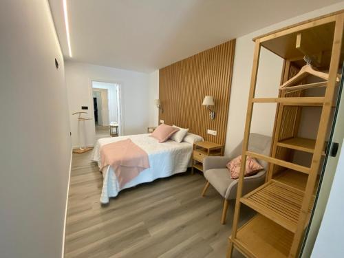 a bedroom with a bed and a chair in a room at Apartamentos Turísticos Vidal Costa in Foz