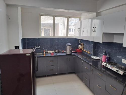 a kitchen with white cabinets and black counter tops at Gokul 2 BHK Entire Flat, Bharat City, Teela Mod, Nr Hindon Airport ,Bhopura , Ghaziabad in Ghaziabad