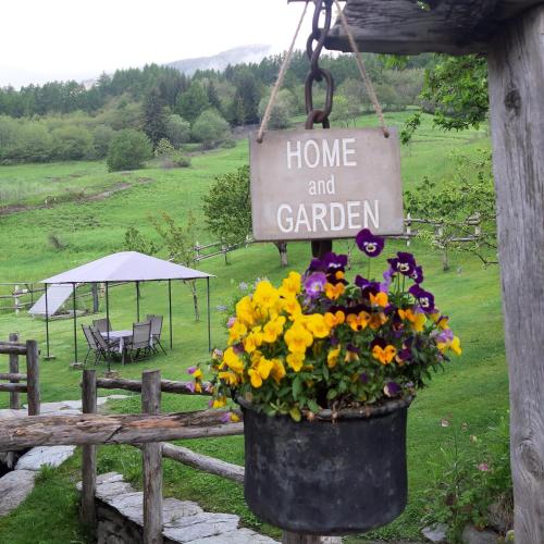 a pot of flowers hanging on a fence with a home and garden sign at CleMaison Antica Dimora Apartments CIR VDA GIGNOD 0013 in Gignod