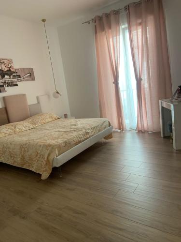 a bedroom with a bed and a window with pink curtains at Il filo di Arianna in Putignano