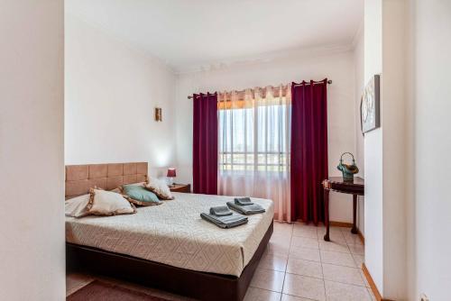 una camera da letto con un grande letto con tende rosse di Lisbon Beach Flat - 4 Guests - Free Parking a Costa da Caparica