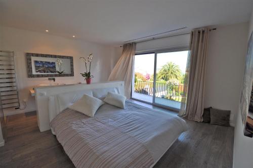 une chambre avec un grand lit avec une grande fenêtre dans l'établissement Superbe villa piscine proche ville et mer au calme, à Nice