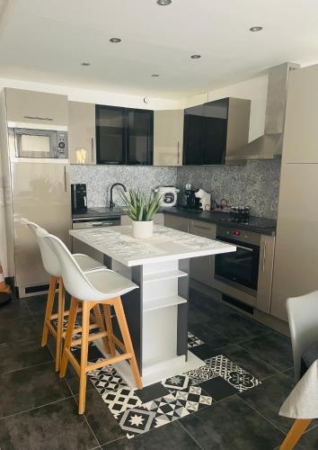 - une cuisine avec un comptoir blanc et des chaises dans l'établissement Appartement 6 couchages Marseillan Plage, à Marseillan