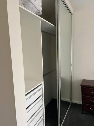 a closet with white cabinets and a mirror at Zen Queendom - Garden View in Newport