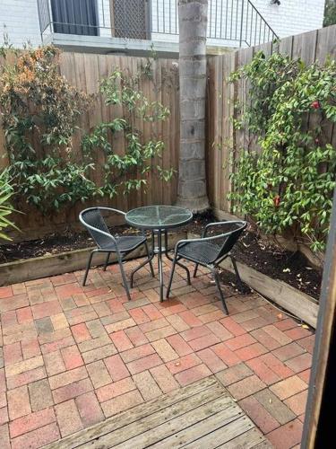 a patio with a table and chairs and a fence at Zen Queendom - Garden View in Newport