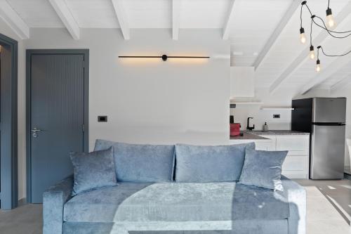 a living room with a blue couch and a kitchen at Ennea Muses Rooms and Suites in Nafplio