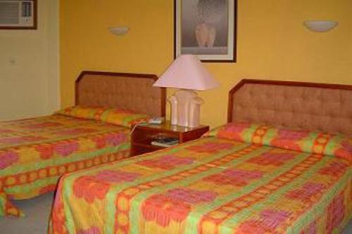 a hotel room with two beds and a lamp at Hotel Debliz in Campeche