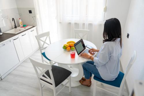 a woman sitting at a table with a laptop at Apartman Kruna in Drvar