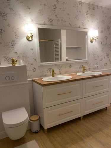 a bathroom with two sinks and a toilet and a mirror at Dworek pod Krzyżtoporem Ujazd Agroturystyka- pokoje do wynajęcia in Iwaniska