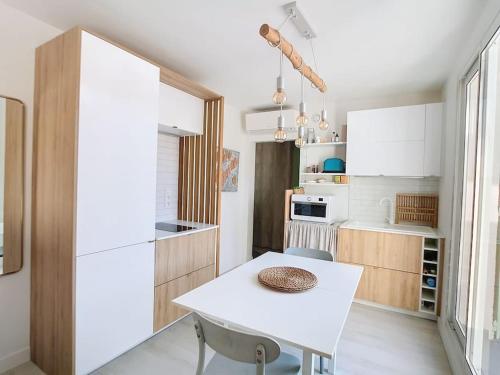 una piccola cucina con tavolo bianco e tavolo bianco di Havre cosy et familial, garage, centre ville, dans la cité des Potiers a Vallauris