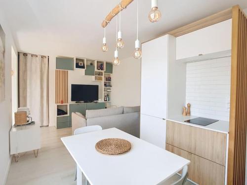 un soggiorno con un tavolo bianco e una cucina di Havre cosy et familial, garage, centre ville, dans la cité des Potiers a Vallauris