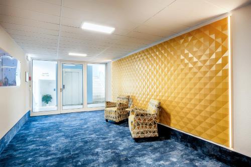 a room with two chairs and a yellow wall at Businesshotel Berlin in Berlin