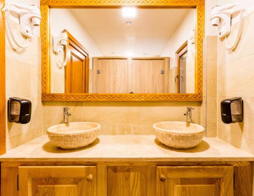 two sinks in a bathroom with a large mirror at Dacii Liberi Resort and Spa in Petrova
