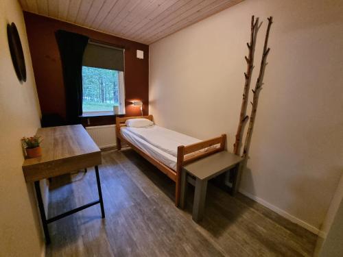a small room with a bed and a table and a window at Marsbäckens lägergård in Västervik