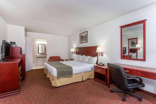 a hotel room with a bed and a desk and a chair at Baymont Inn & Suites in Manning