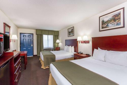 a hotel room with two beds and a television at Baymont Inn & Suites in Manning