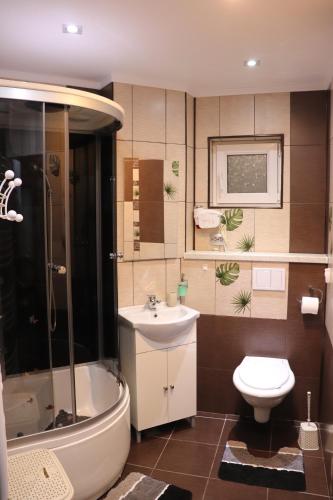 a bathroom with a sink and a tub and a toilet at Apartament Bianca in Năvodari