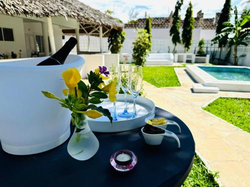a table with a bottle of champagne and flowers on it at Lilo Cottages in Watamu