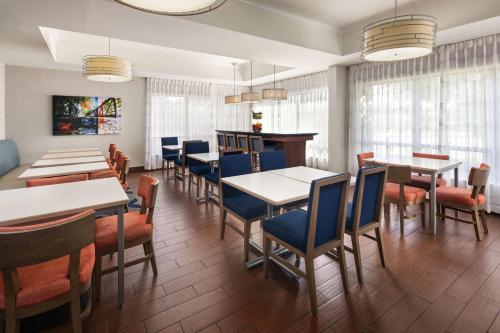 a dining room with tables and chairs and windows at Hampton Inn Minneapolis Northwest Maple Grove in Maple Grove