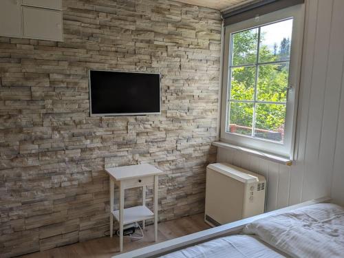 ein Schlafzimmer mit einer Ziegelwand und einem TV an der Wand in der Unterkunft Hellaberg IV Ferienhaus am Waldrand mit Sauna & großer Terrasse in Langenbach