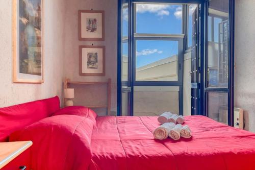 a red bed in a room with a large window at Villa Angelina - Mare Privato in Cannizzaro