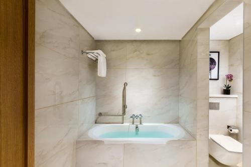a bathroom with a bath tub and a sink at Millennium Place Mirdif in Dubai