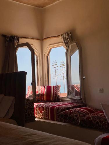 a bedroom with two windows and a bed with pillows at Riad Sahara Sunset Beach Douira Agadir in Douaïra