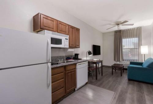 a kitchen with a white refrigerator and a living room at MainStay Suites Extended Stay Hotel Casa Grande in Casa Grande