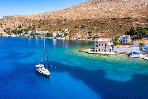 a boat in the water next to a small island at Nimporio View Villa in Symi