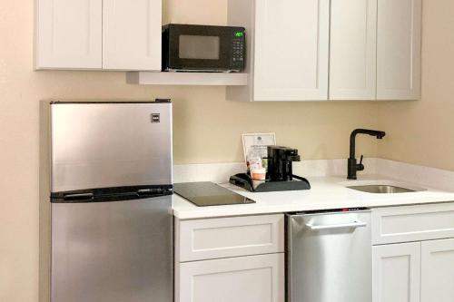 a kitchen with white cabinets and a stainless steel refrigerator at Comfort Suites Columbia Gateway in Elkridge