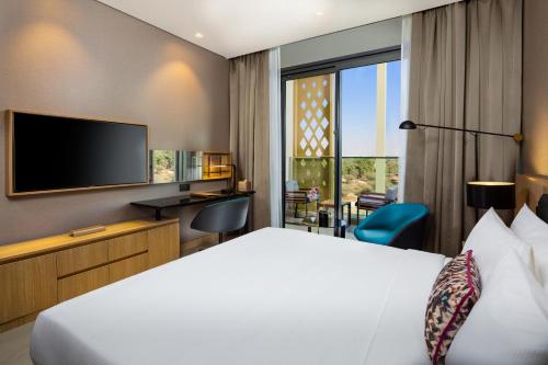 a hotel room with a bed and a flat screen tv at Millennium Place Mirdif in Dubai