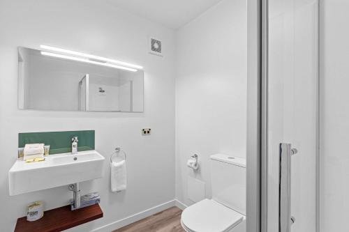 a white bathroom with a sink and a toilet at Comfort Hotel Benvenue in Timaru