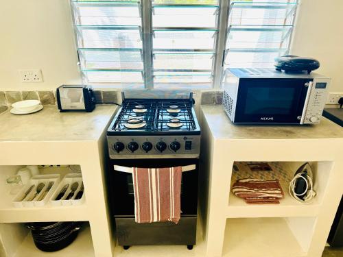 a kitchen counter with a stove and a microwave at Lilo Cottages in Watamu