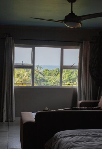 a bedroom with two large windows with a view of the ocean at Utopia in Palm Beach in Port Edward