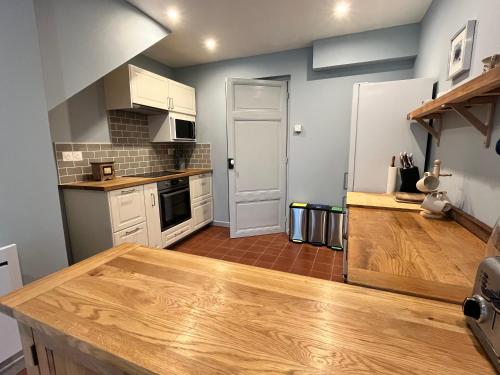 une cuisine avec des armoires blanches et un comptoir en bois dans l'établissement Cute 2 bed cottage - Fources, Gascony, à Fourcès