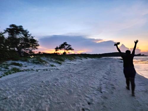 a man running on a beach with his arms in the air at Beachside calm, Footsteps to the sand and sea in Silver Sands