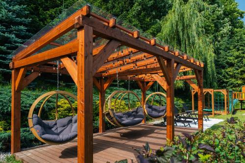 a wooden pergola with chairs on a wooden deck at Hotel Smile Pieniny in Szczawnica