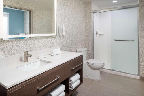 a bathroom with a sink and a toilet and a mirror at Home2 Suites By Hilton Wilmington Medical Park Downtown in Wilmington