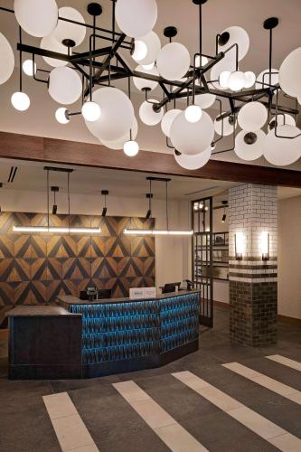 a lobby with a large chandelier and a bar at Hotel Nickel Plate Fishers, Tapestry Collection By Hilton in Fishers