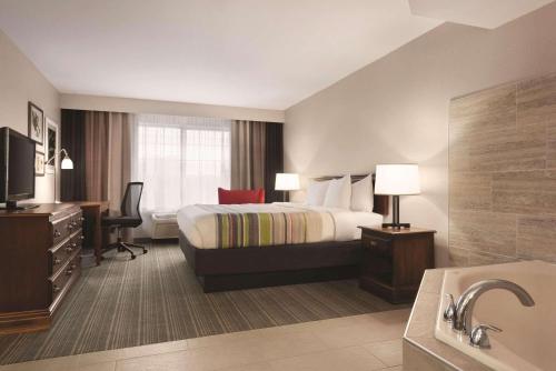 a hotel room with a bed and a bathroom at Country Inn & Suites by Radisson, Michigan City, IN in Michigan City