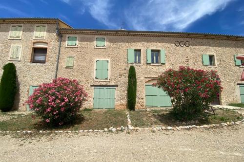 a brick building with green garage doors and pink flowers at 04B2 Beautiful studio in a mas provençal - pool in Brunet