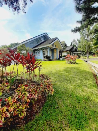 ein Haus mit einem grünen Garten mit Blumen in der Unterkunft Vila kota bunga in Cikundul