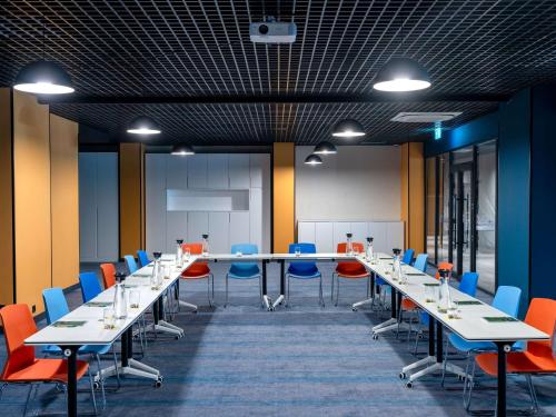 a conference room with long tables and blue chairs at ibis Styles Batumi Hotel in Batumi