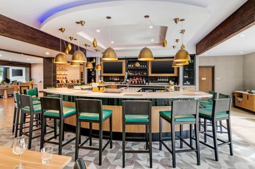 a restaurant with a bar with green chairs at Cambria Hotel North Conway in North Conway