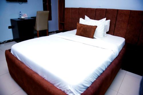 a large bed in a hotel room with a pillow on it at Ovic Hotel in Benin City