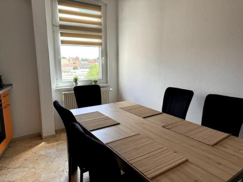 a dining room table with black chairs and a window at Wohnung nahe Bahnhof und dem Goitzschesee in Bitterfeld